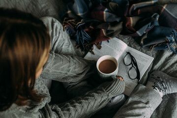 Winter still life concept. Young girl holding cacao mug, reading book. Season holiday, hygge concept