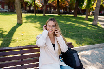 Wall Mural - Young scandinavian blonde woman talking on mobile while sitting on a