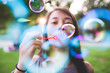 © Image Source Limited - Close up of young woman in park blowing bubbles