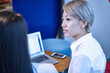 © Image Source Limited - Woman in office using laptop, talking with colleague