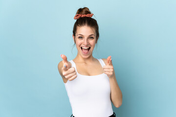 Sticker - Young caucasian woman isolated on blue background pointing to the front and smiling