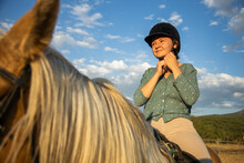 Contemplative Woman On Horse Under Cloudy Sky In Countryside