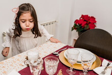 Girl Blowing Wax Candles Placed On Dinner Christmas Table