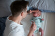 © RealPeopleStudio - Worried oung father looking on thermometer holding his newborn baby in hands.