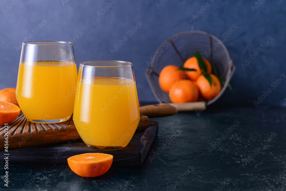 Glasses with tasty mandarin juice on dark background