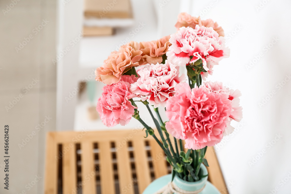 Vase with beautiful carnations on table in room
