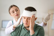 © Pixel-Shot - Doctor applying bandage onto head of young man in clinic