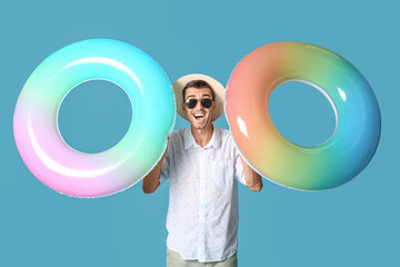 Wall Mural - Young man with inflatable rings on color background