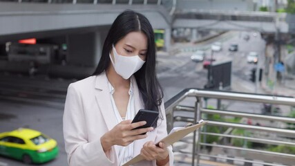 Wall Mural - attractive professional asian business woman using mobile phone wearing protective face mask prevent covid-19 virus  in the city outdoor