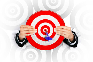 Businessman holds dartboard with dart on target