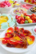 Different colorful flavored fruit candy on plates on a white wooden background. Vertical view