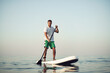 © fotofabrika - Young man in t-shirt and shorts floating on SUP board