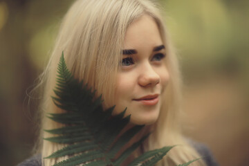 eco concept girl portrait fern, young adult model blonde, green leaf on face