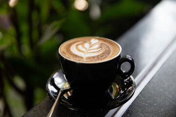 Cup of tasty cappuccino with latte art on wooden table background.