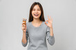© sitthiphong - Asian woman wearing braces holding ice cream and shows ok sign on grey background.