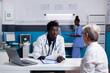 © DC Studio - Black medical specialist consulting elderly patient at desk in doctors office. African american medic discussing with senior woman for healthcare issues treatment. Appointment checkup