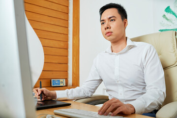 Wall Mural - concentrated young designer using graphic table when working on logotype for new product