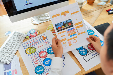 Wall Mural - ui designer holding page with layout of new social media mobile application