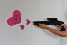 Shooting Out Pink Heart-Shaped Targets. Asian Lady Playing With A Toy Shotgun, Shooting Out Pink Heart-shaped Targets.