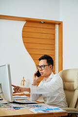 Wall Mural - graphic designer talking on phone with customer discussing changes that have to be done