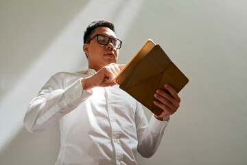 Wall Mural - businessman in white shirt and glasses checking document or e-mail on tablet computer, view from bel