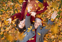 Grandmother And Granddaughter Lying On Foliage And Enjoy The Autumn