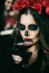 Wall Mural - Vertical closeup of a woman with Halloween makeup holding a glass of dark liquid.