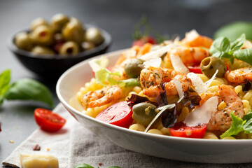 King prawn pasta salad with marinated green olives, cherry tomatoes and parmesan cheese shavings. Healthy food.