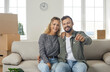 © Studio Romantic - Portrait of happy young married couple sitting on sofa in new house or apartment, showing key to new home, looking at camera and smiling. Real estate, mortgage, buying property of your dream concept