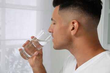 Wall Mural - Man drinking tap water from glass at home, closeup