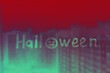 © ksenija1803z - Handwritten lettering green Halloween with scary face on rainy red glass window with raindrops