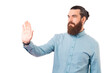 Serious bearded man is making stop gesture with his hand over white background.