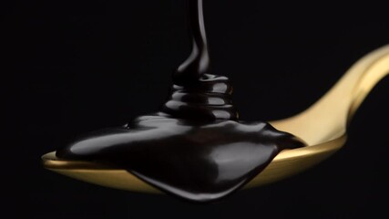 Wall Mural - Chocolate. Pouring liquid dark chocolate in golden spoon. Confectionery concept. 4K UHD video 