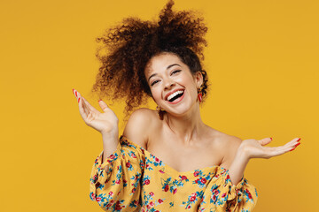 Wall Mural - Young happy satisfied excited fun cheerful amazed woman 20s with culry hair wear casual clothes spread hands look camera isolated on plain yellow background studio portrait. People lifestyle concept.