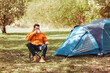 © Syda Productions - camping, tourism and travel concept - happy man drinking tea at tent camp