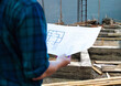 © Wasan - Construction project inspector engineer is working on a construction site holding a construction plan.