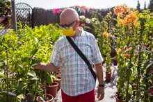 Elderly Buyer In Sterile Mask Choosing Plants In Garden Shop