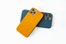 Modern mobile phones in blue and yellow leather cases on a white background. Modern smartphones with triple lens cameras