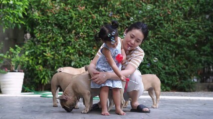 Wall Mural - A mom with bulldogs and her cute little girl blowing bubbles in the yard