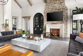 beautiful living room in new traditional style luxury home with stone fireplace surround, vaulted ce