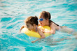 © Natalya Temnaya - Two young smiling girls in a swimsuit bathes play in a pool with blue clear water in blue swimming glasses. Summer. Rest. Vacation.