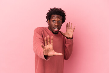 Wall Mural - Young african american man isolated on pink background being shocked due to an imminent danger