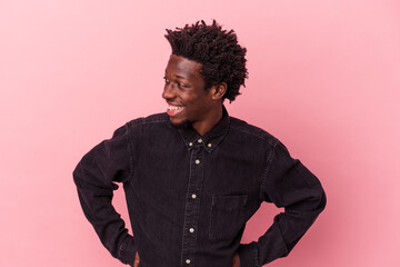 Wall Mural - Young african american man isolated on pink background laughs happily and has fun keeping hands on stomach.