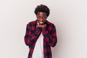 Wall Mural - Young african american man isolated on white background  keeps hands under chin, is looking happily aside.