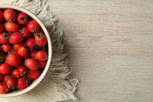 Ripe Rose Hip Berries In Bowl On Wooden Table, Top View. Space For Text