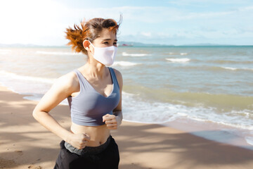 Asian woman jogging by the beach in the morning of warm summer.