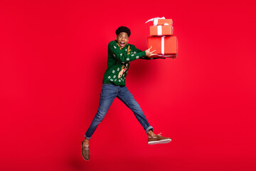 Wall Mural - Photo of funky sporty guy jump carry pile giftboxes scream open mouth wear green deer sweater isolated on red background