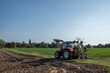 Working tractor cultivate and plough the soil on agricultural farm in countryside area in Europe.