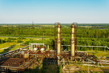 Two old absorption columns of gas refueling against the background of a summer landscape.