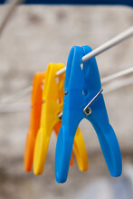 Closeup Of Blue, Yellow, And Orange Clothespins On A Wire